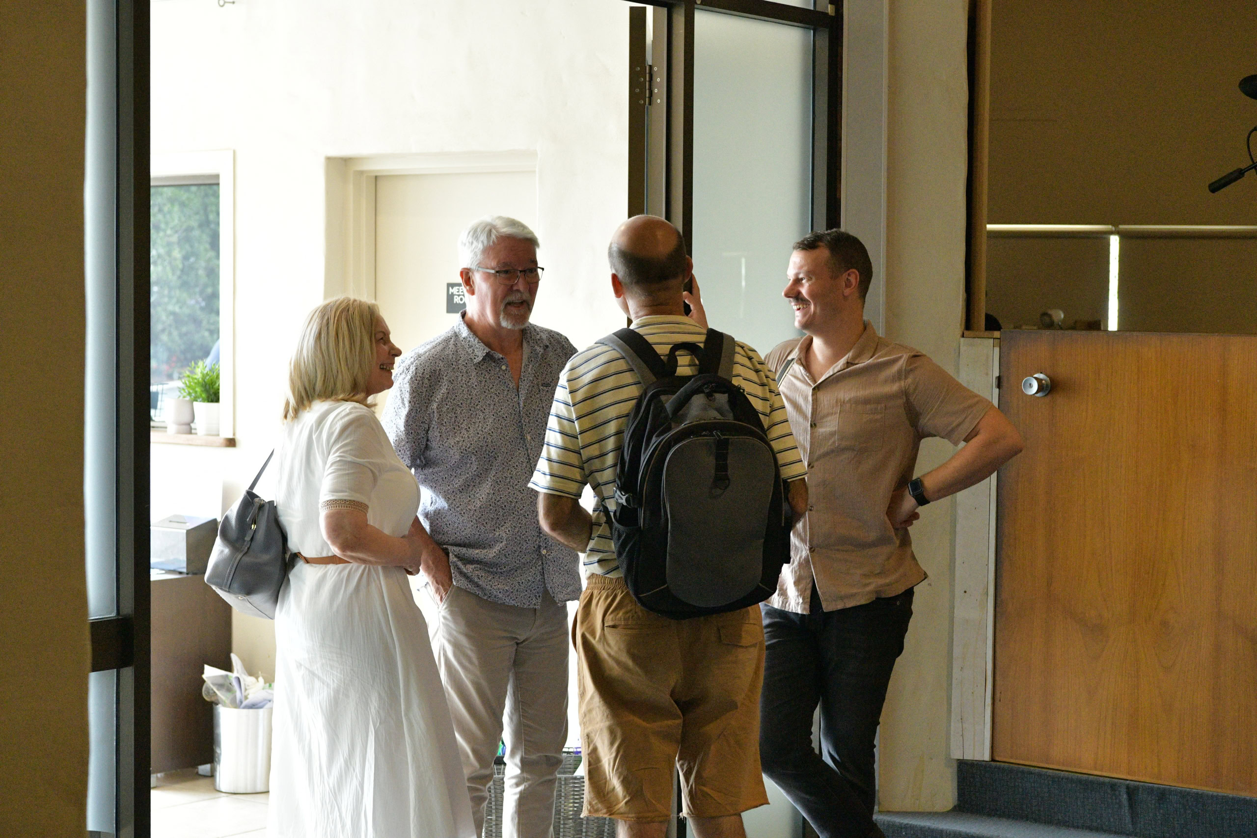 A small group of adults chats near the entrance of a church, smiling and engaged in conversation | Easter at Oasis Church